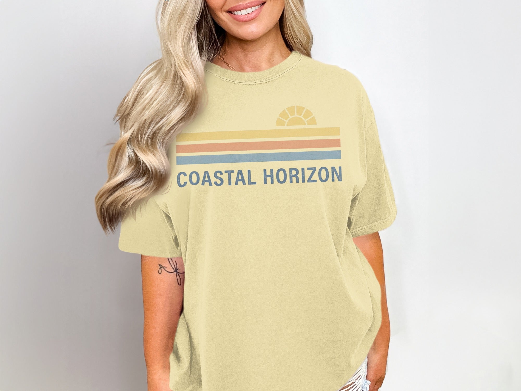 Yellow t-shirt with "Coastal Horizon" text and a stylized sun graphic.