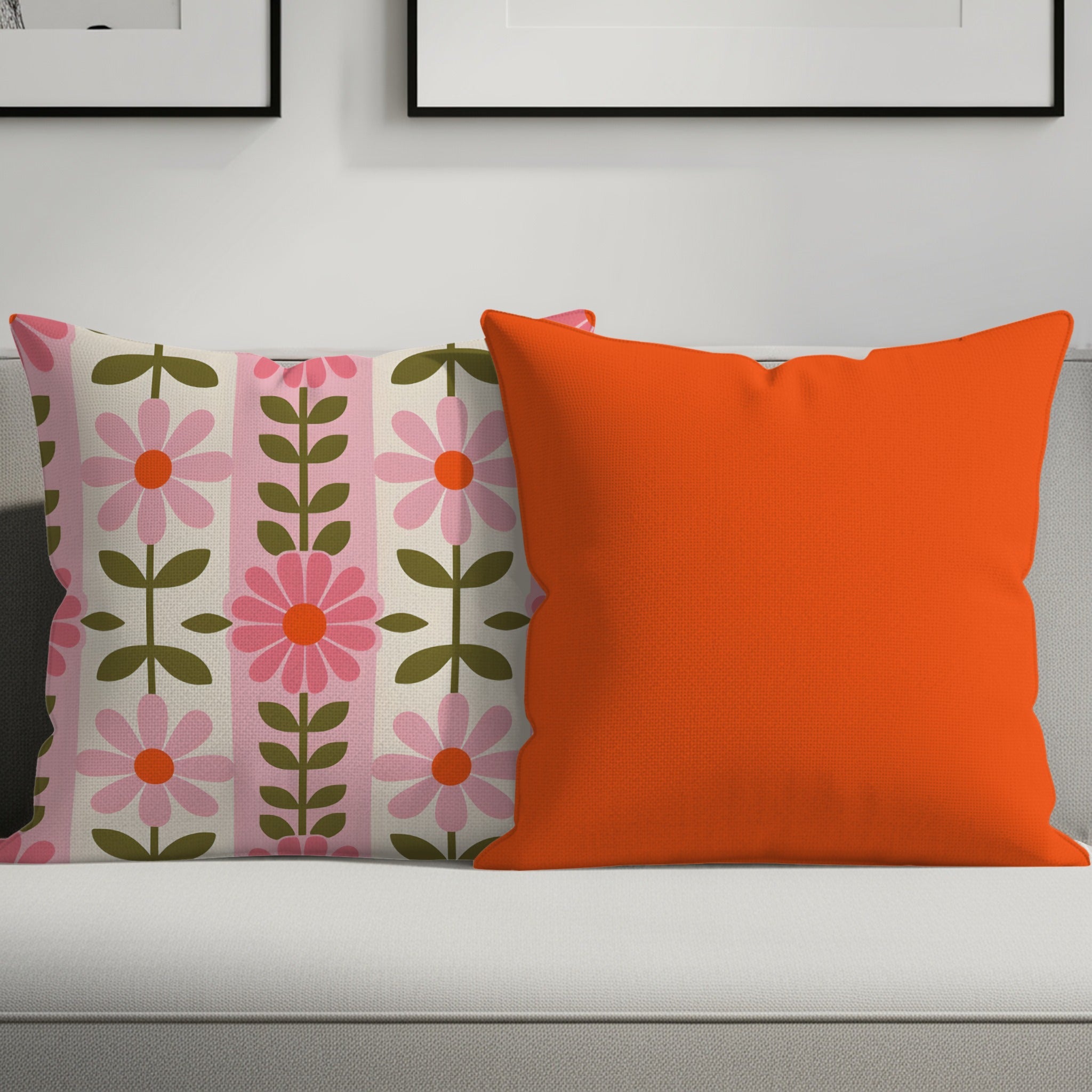 Two decorative throw pillows on a sofa, one with a floral pattern, one orange.