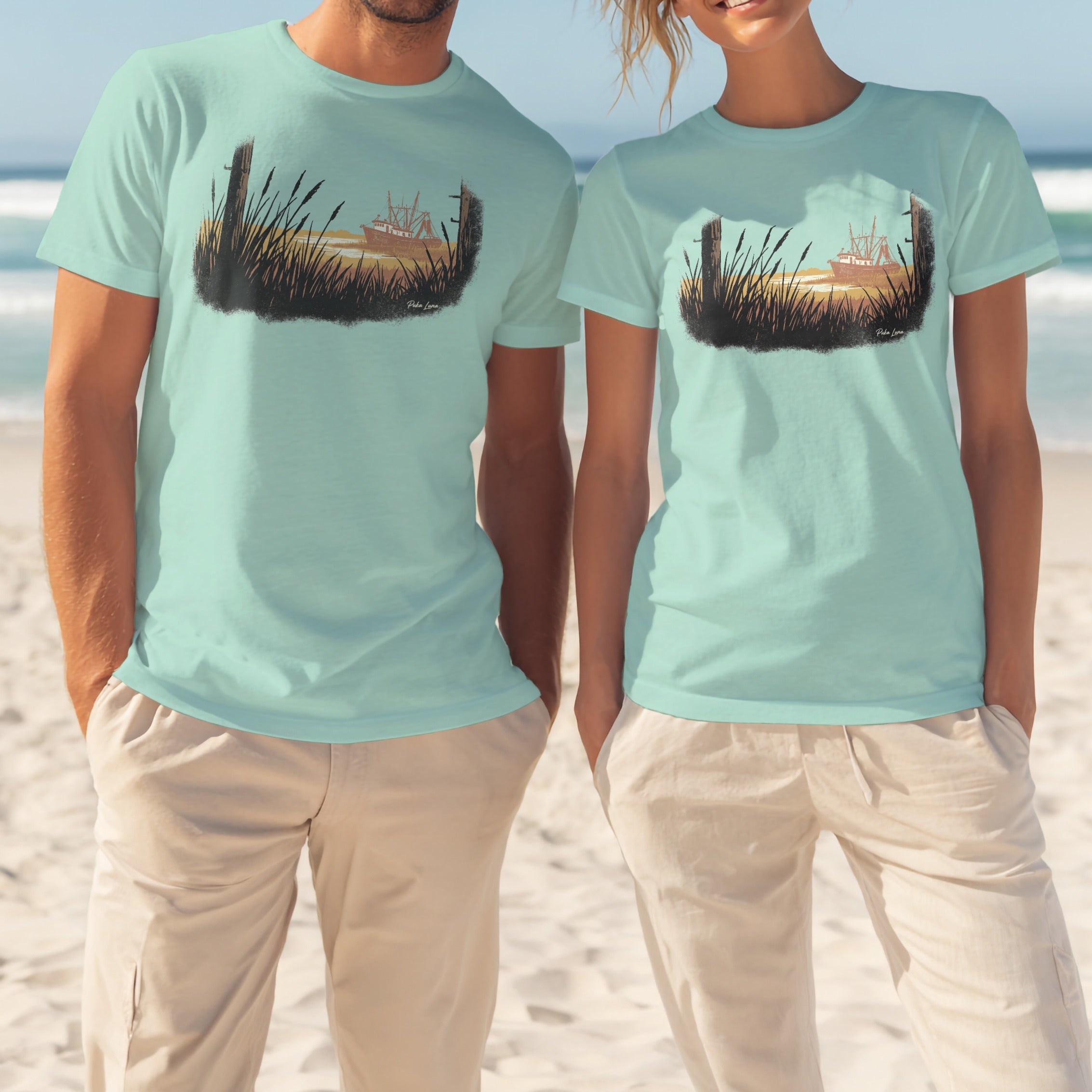 Two people wear light teal t-shirts with a sunset landscape graphic.