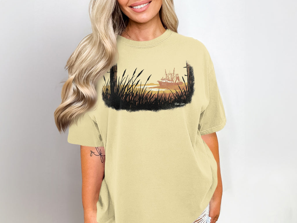 T-shirt with watercolor graphic of a shrimp boat at sunset among tall grass.