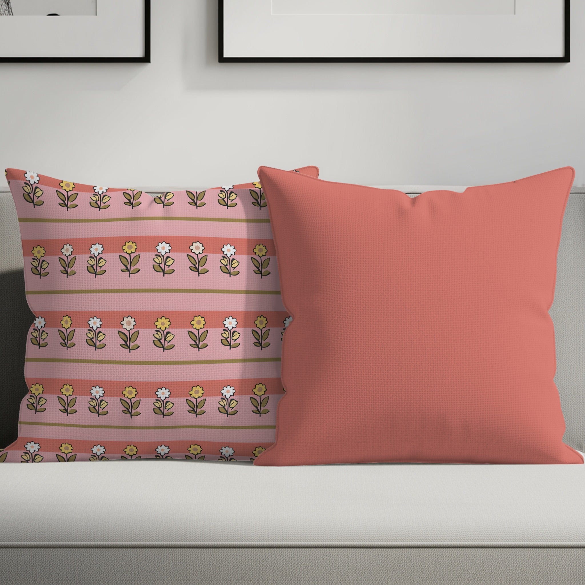 Two throw pillows on a couch, one floral patterned, the other coral.