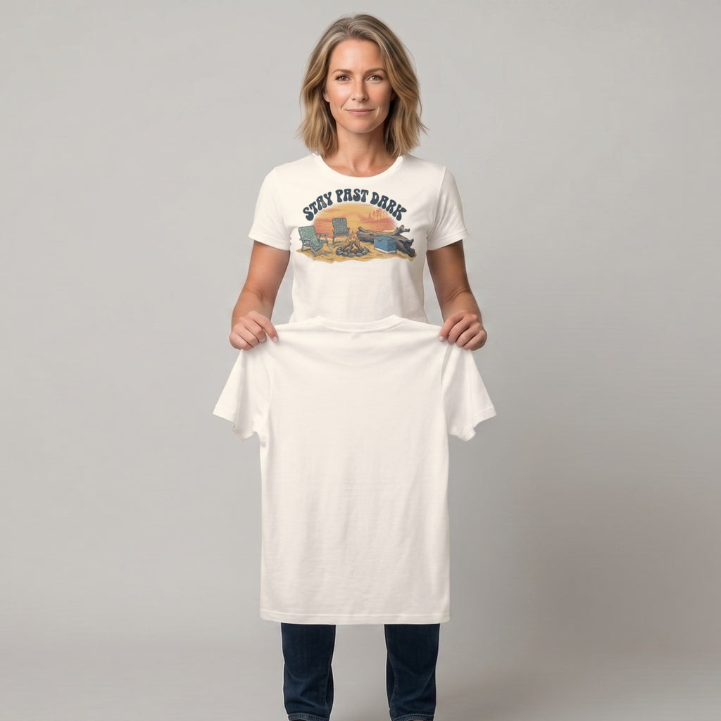 Woman holding up cream t-shirt with "Stay Fast Dark" graphic of campfire and canoe.