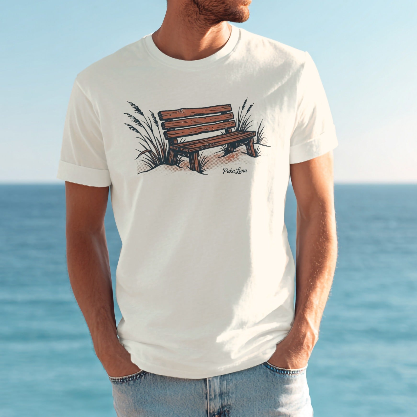 White t-shirt with illustration of a wooden bench on sand and beach grass.