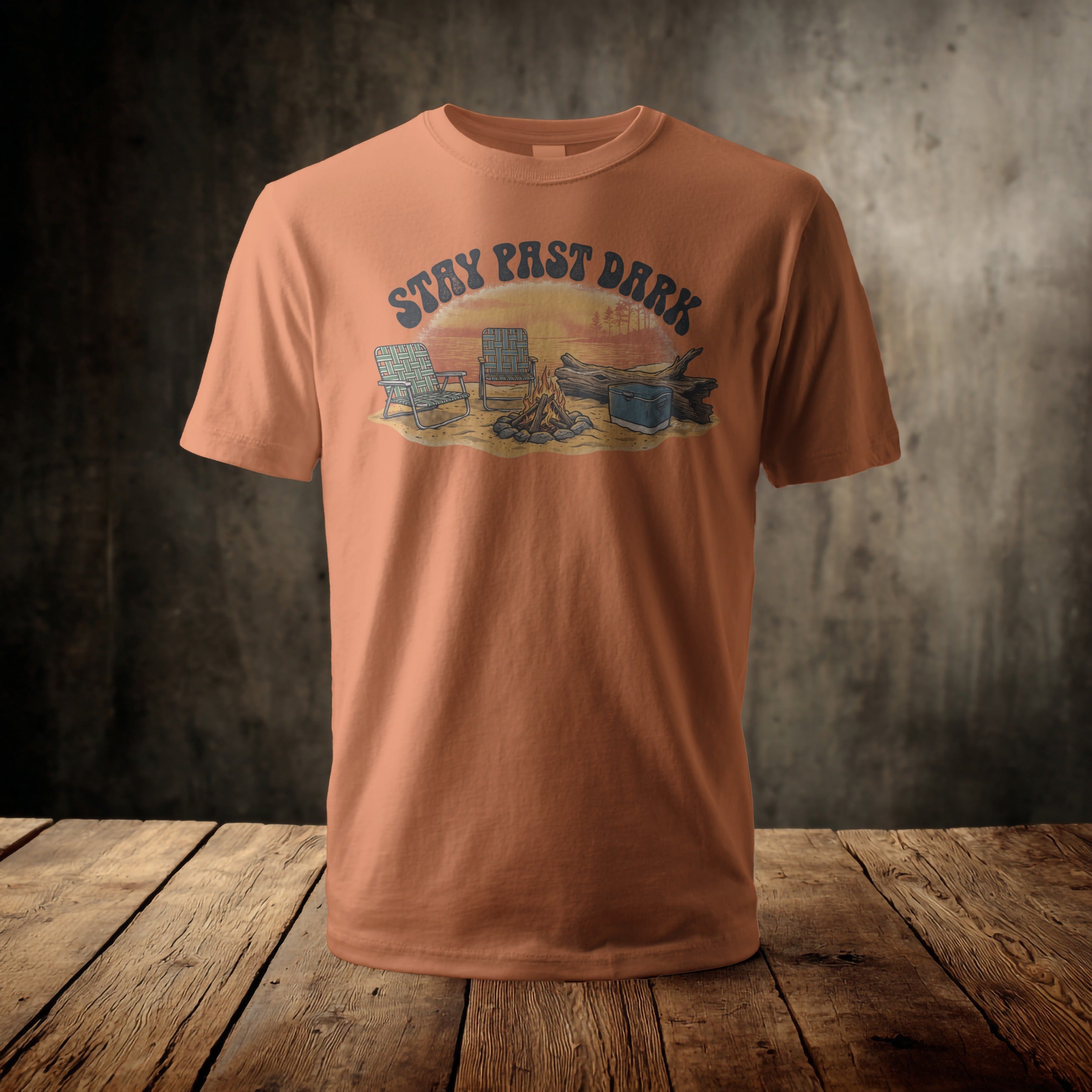 Orange t-shirt with a graphic of a campfire scene at sunset.