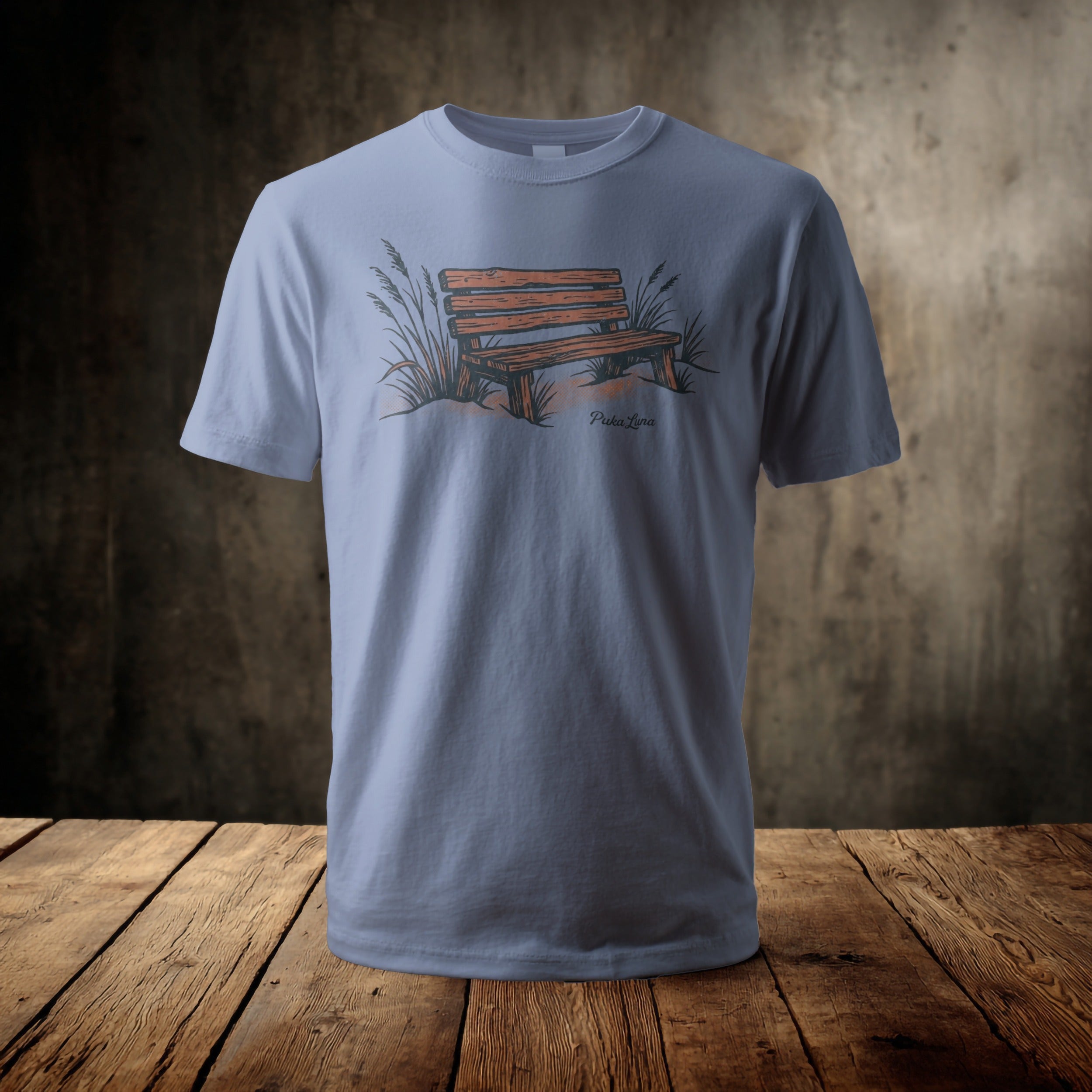 Light blue t-shirt with a wooden park bench and grass graphic.
