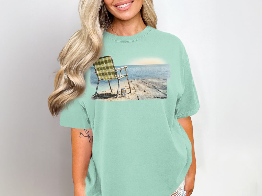 Green and white plaid beach chair on a pier overlooking the ocean.