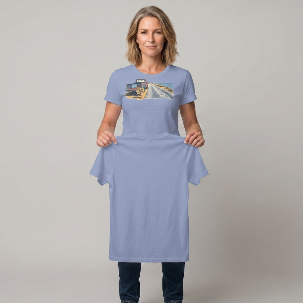 Woman holding light blue t-shirt with printed graphic of a vintage truck on a dirt road.