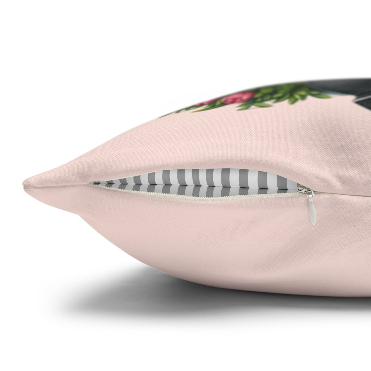 Pink pillow with a floral design and striped zipper detail.