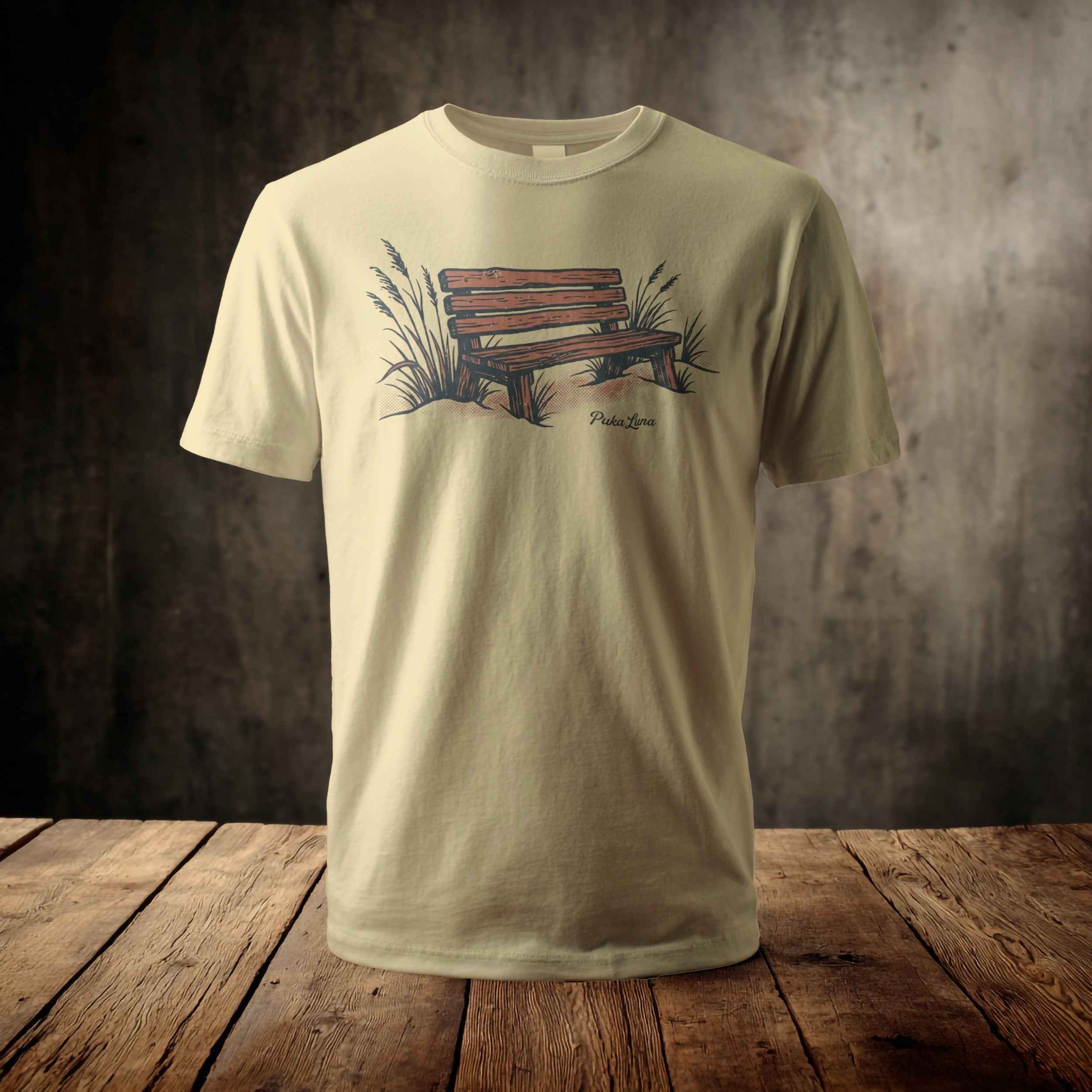 Cream t-shirt with a sketch of a wooden park bench and grass.