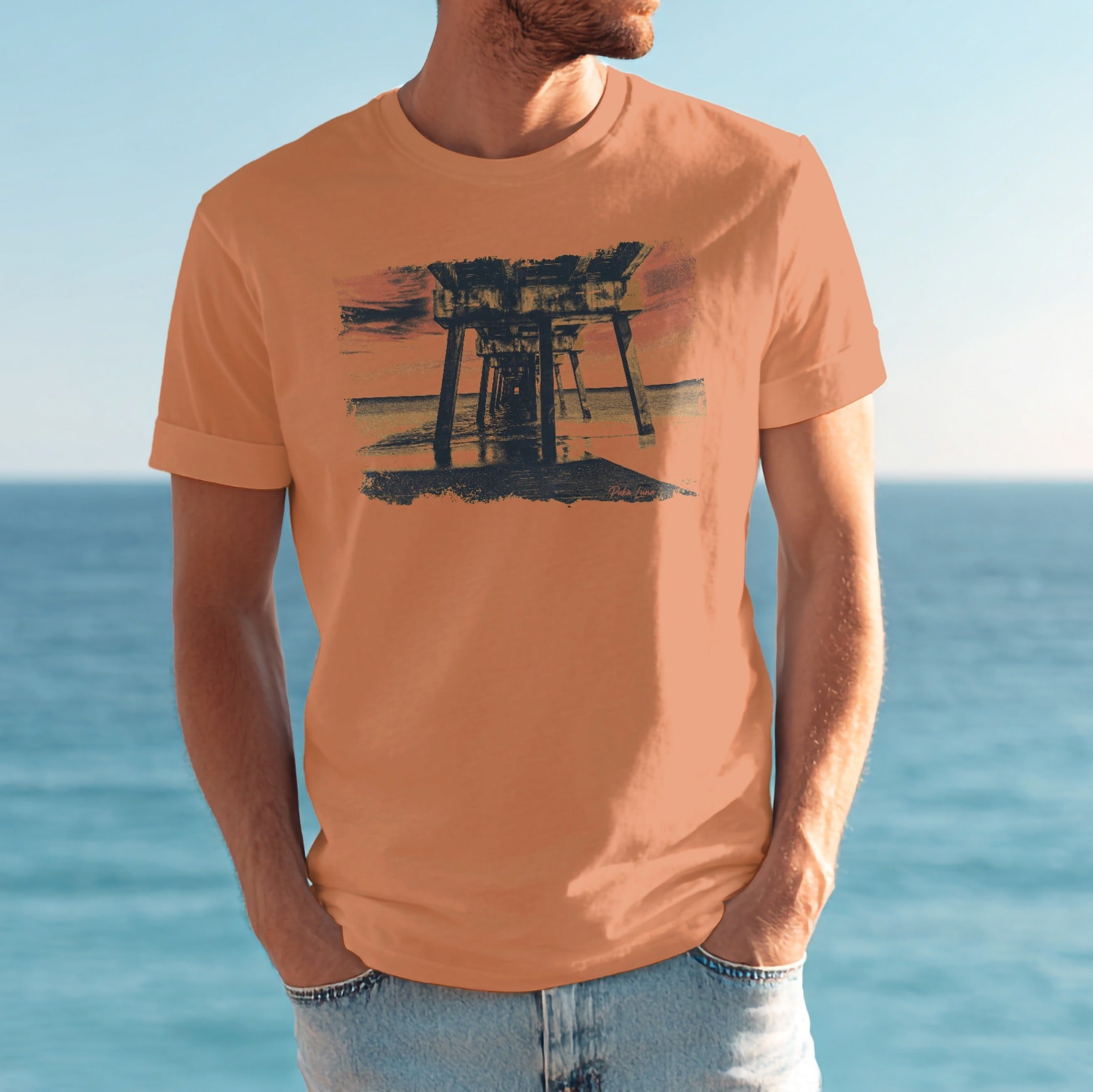 Man wearing orange t-shirt with sunset pier graphic.