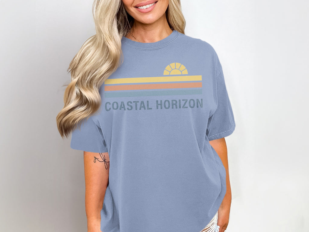 Blue t-shirt with "COASTAL HORIZON" text and a striped sunset graphic.