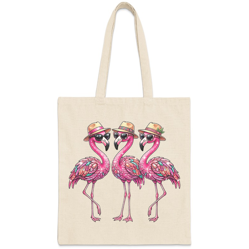 Three cartoon flamingos wearing sunglasses and hats on a canvas tote bag.