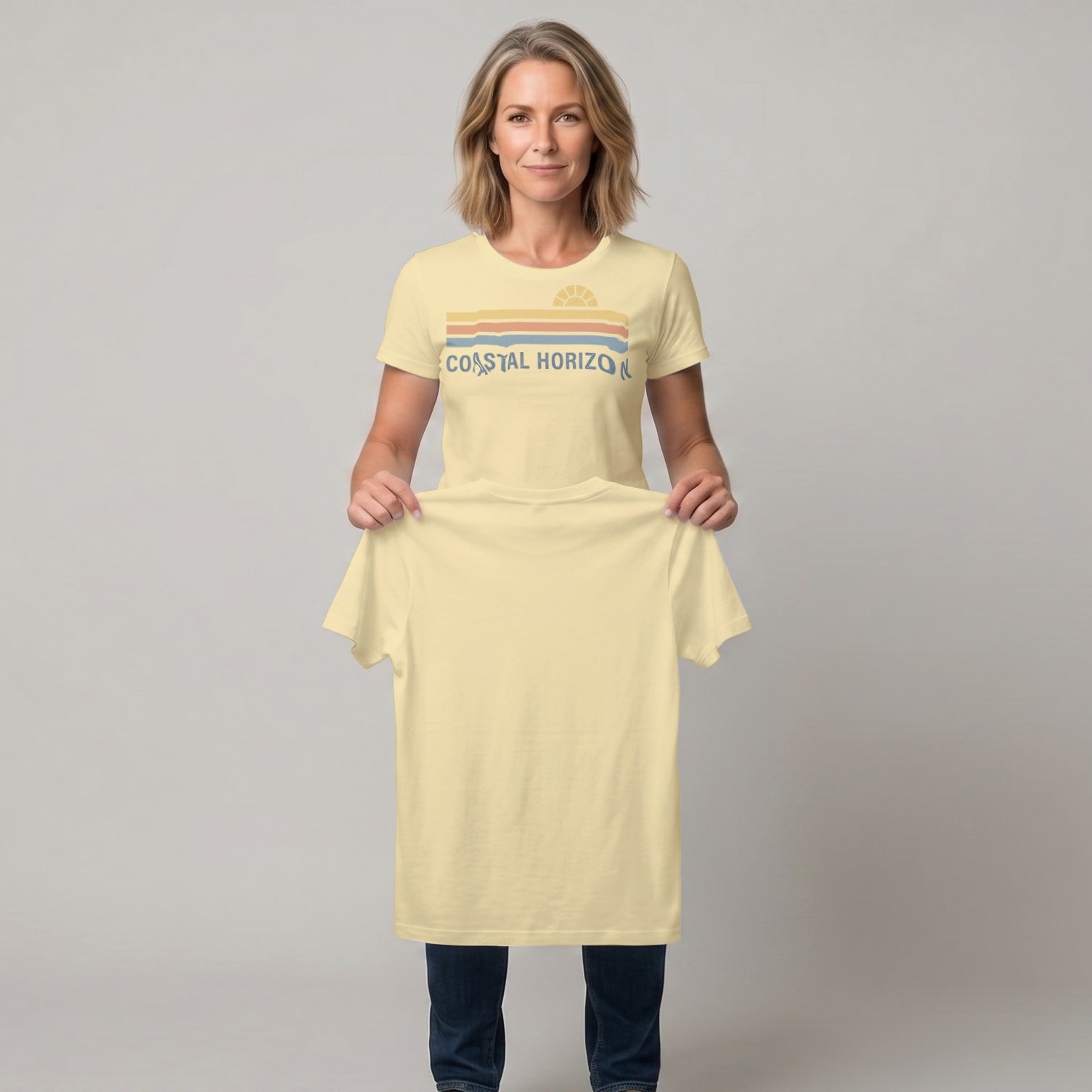 Woman holding a light yellow t-shirt with a retro sunset design and "COASTAL HORIZON" text.