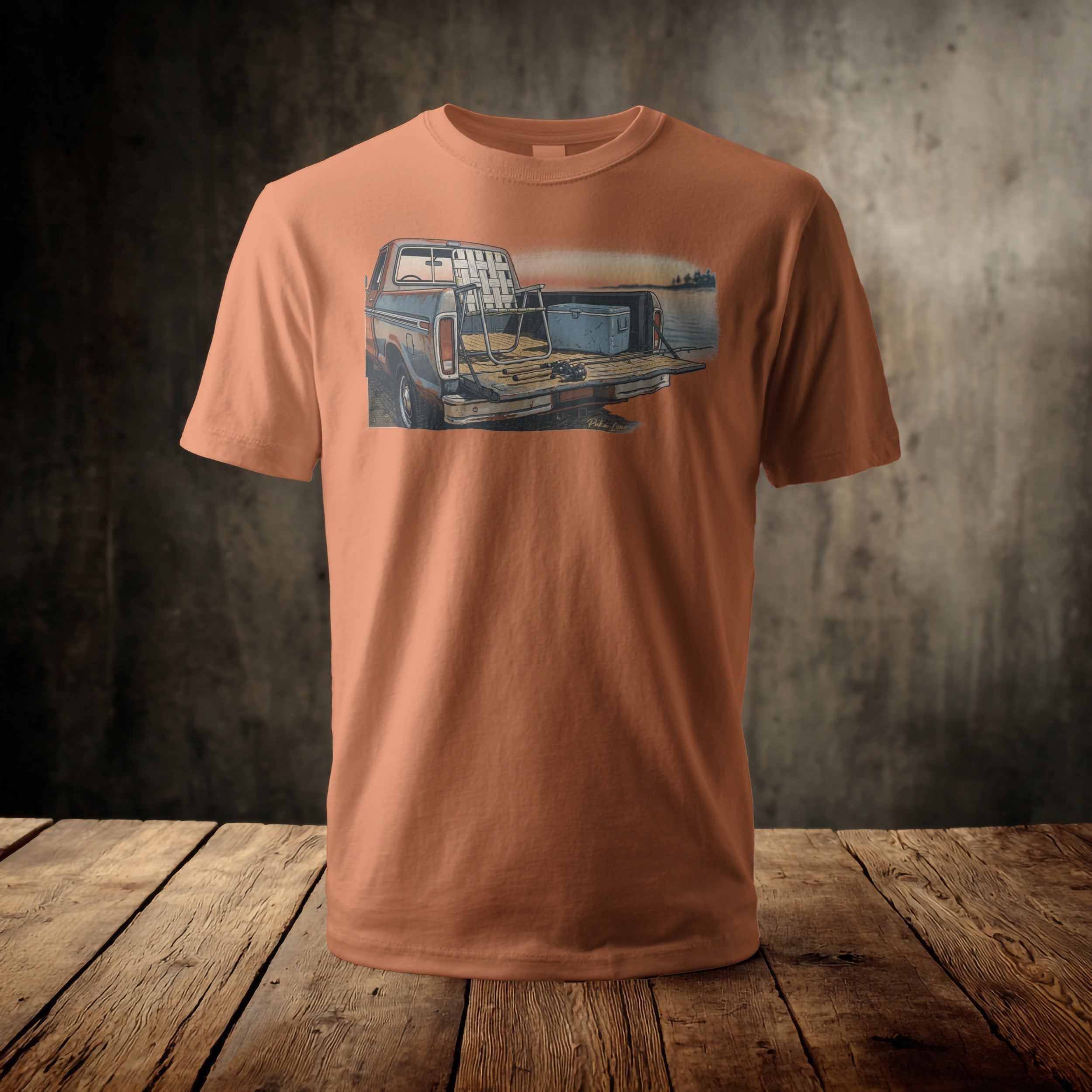Orange t-shirt with a graphic of a fishing truck loaded for a trip.