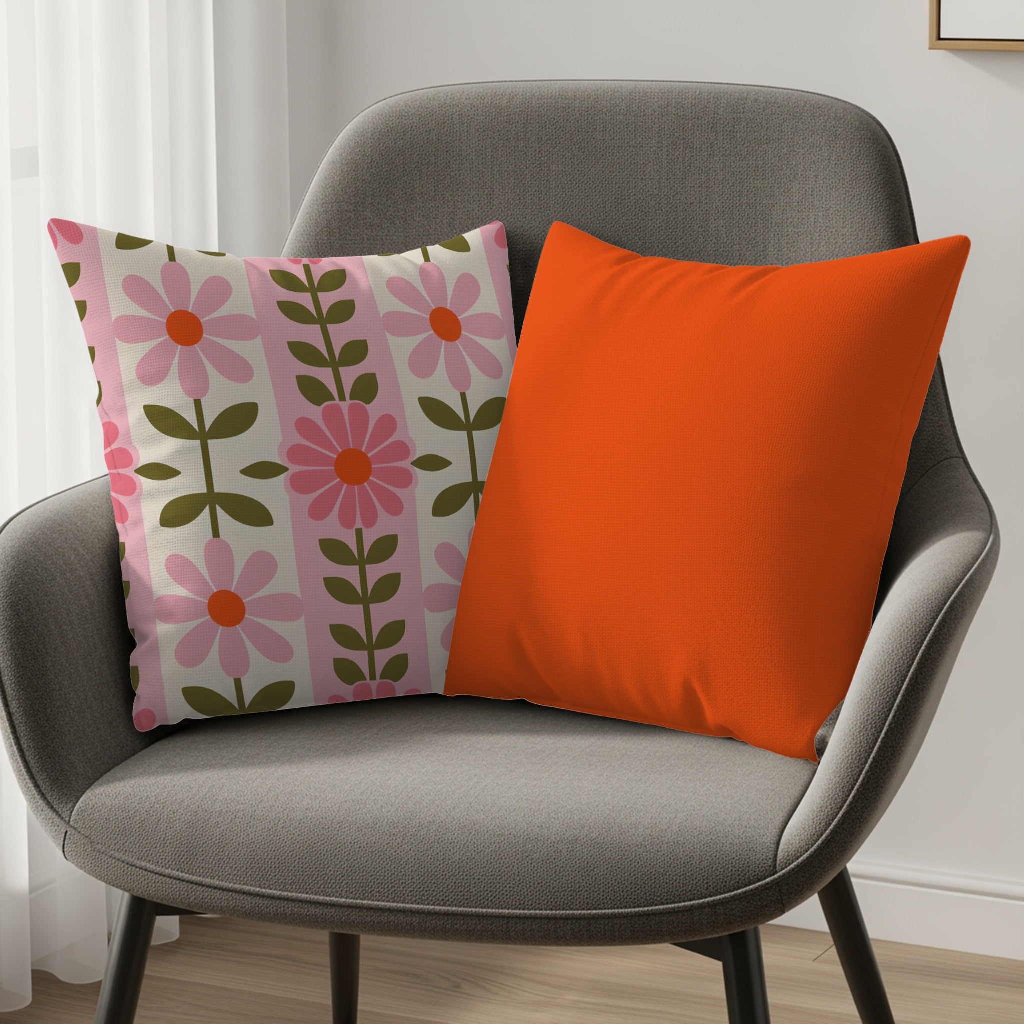 Gray armchair with two decorative throw pillows, one floral, one orange.