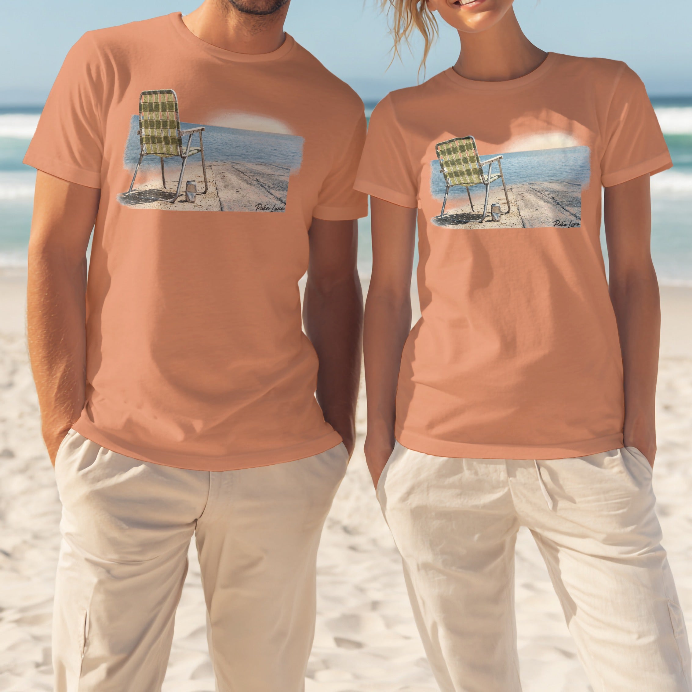 Two people wear peach t-shirts featuring a beach chair by the water.