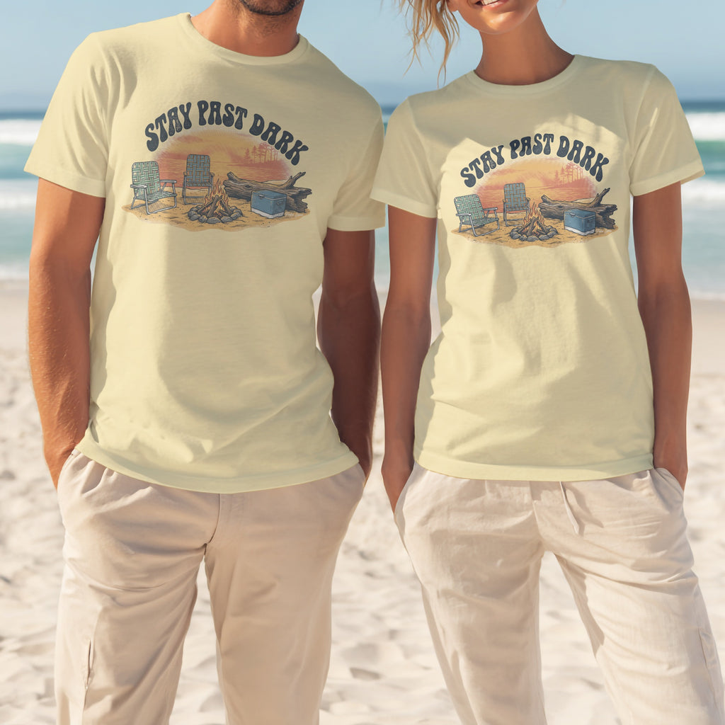 Two people wear light yellow t-shirts with "Stay Past Dark" text and campfire graphic.
