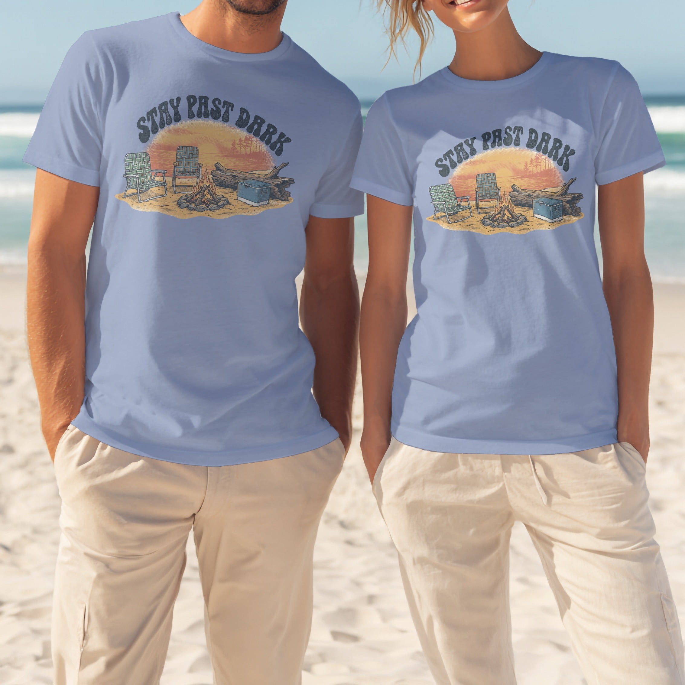 Two people wearing light blue t-shirts with "STAY PAST DARK" text and campsite graphic.