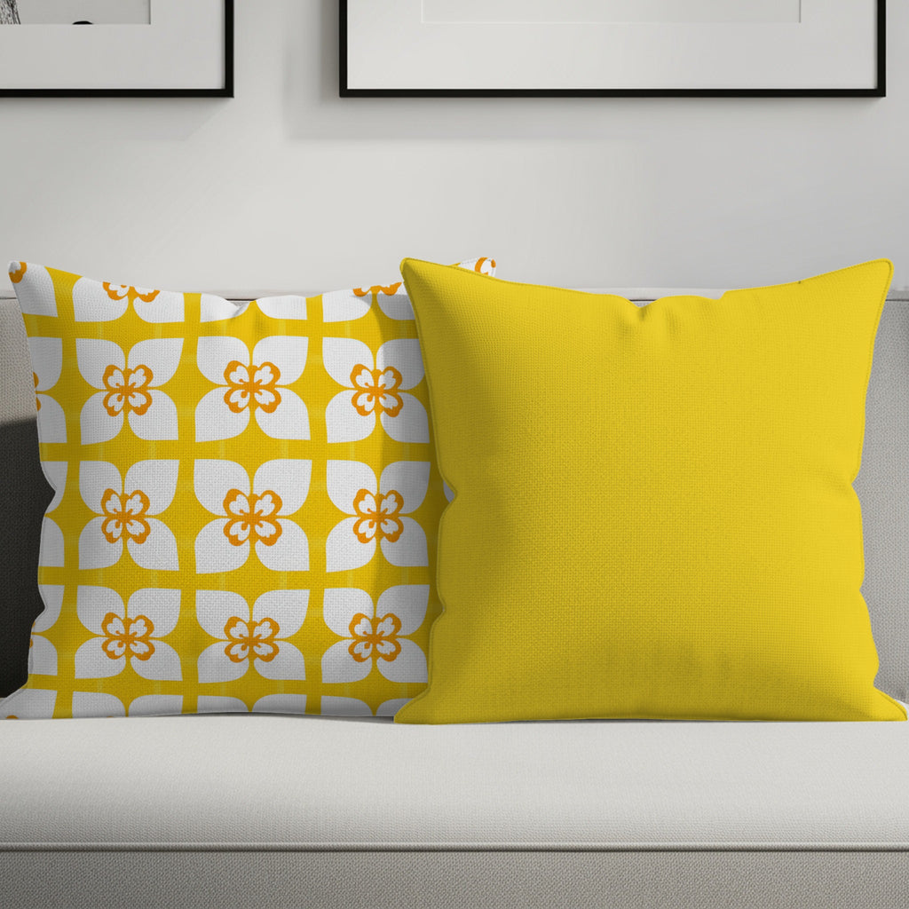 Two throw pillows on a couch: one with a yellow floral pattern, one solid yellow.