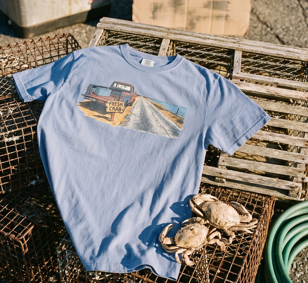 Light blue t-shirt with graphic of vintage truck on a coastal road and two crabs.