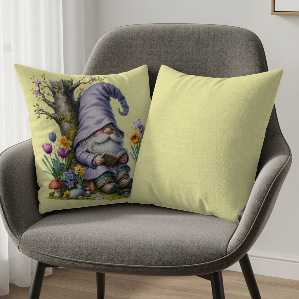 Gnome reading a book under a tree with flowers, next to a yellow pillow.