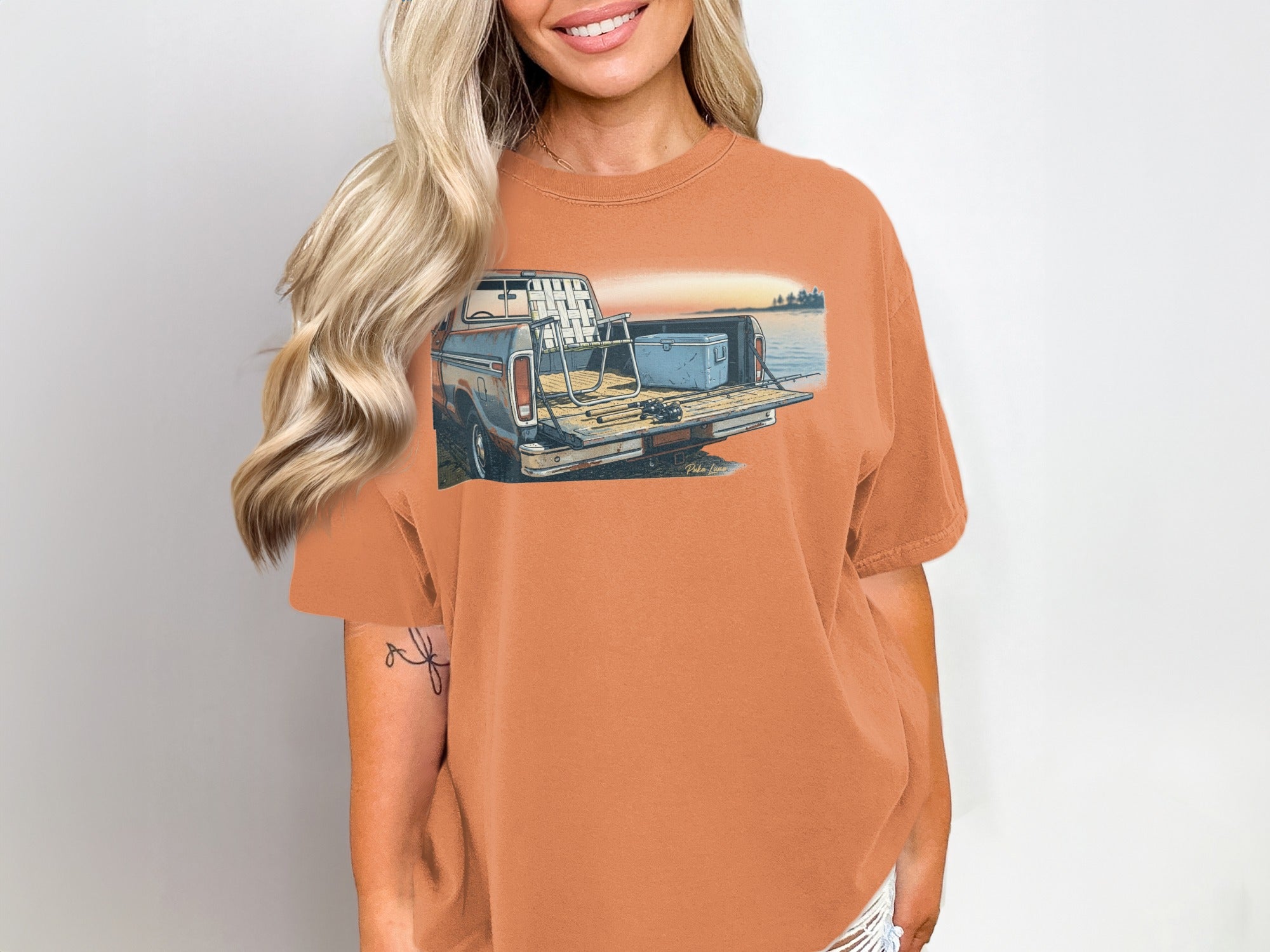 Orange t-shirt with a graphic of a pickup truck with fishing gear in the bed.